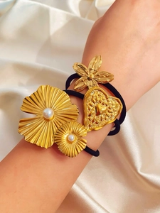 Dettaglio di tre elastici per capelli con fiori dorati 18k, perle e un cuore in rilievo