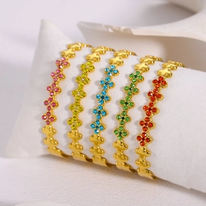 Elegante vergulde armbandenset met kleurrijke strass klavertjes op een wit kussentje
