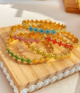 Detailweergave van vijf vergulde klaverarmbanden bezet met kleurrijke edelstenen