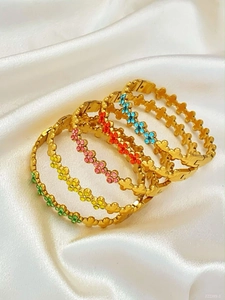 Detail van gouden klaverarmbanden met levendige veelkleurige kristallen strass-steentjes