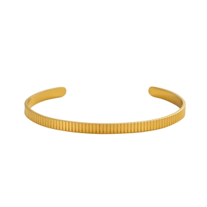 Detailed view of the gold fluted cuff bracelet featuring a vertical ribbed metal texture