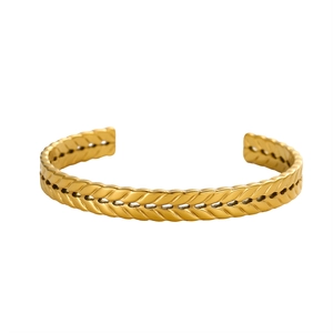 Macro shot of gold cuff bracelet featuring intricate double-row wheat ear texture patterns