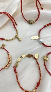 Detailansicht der gewebten roten Armbänder mit Goldmünzen und Glücksanhängern