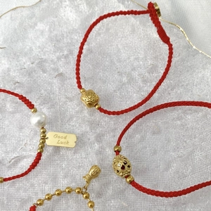 Rotes geflochtenes Armband mit goldenen Glücksbringern und Perle im schicken China-Stil