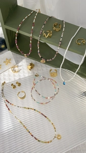 French-style pearl necklaces and gold rings displayed on green wooden stands