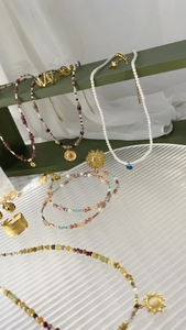 Detail shot of pearl necklace and colorful beaded jewelry on a dark green display stand