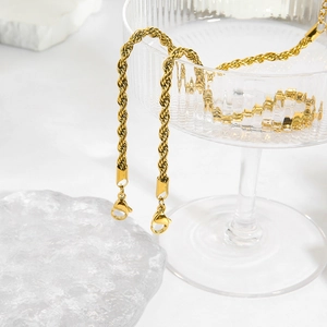 Détail d'une chaîne corde dorée avec fermoirs mousquetons sur le rebord d'un verre