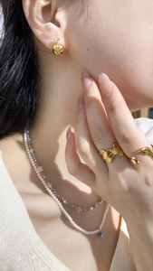Close-up of French style pearl necklace with blue teardrop pendant and gold jewelry set