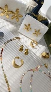 Close-up of pearl necklaces and gold floral earrings on a textured waffle background