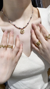French style necklace with tiny pearls and gold rings set on female model wearing white sweater