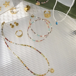Elegant gold necklace with blue pendant and pearls on cream textured background