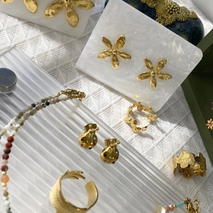 French style gold pearl necklace with floral earrings and ladybug charms on marble