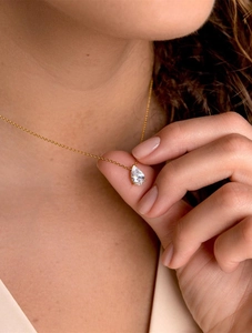 Close-up of elegant gold chain necklace with a pear-cut teardrop zircon pendant on neck