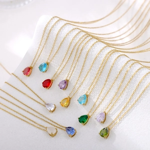 Detailed row of gold teardrop necklaces with colorful crystal pendants on white display