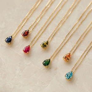 Detail of colorful waterdrop gemstone pendants in gold plating on marble background