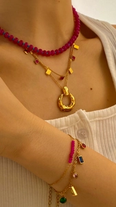 Detailed view of layered beaded necklaces and multi-colored gemstone charm bracelets