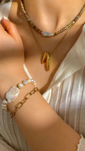 Set di collane con perle barocche e bracciali dorati a strati su top bianco a coste