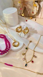 Detailed close-up of 18K gold-plated jewelry set with vibrant red and blue beads