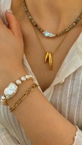 Collane con perle barocche e oro a strati indossate da una modella elegante