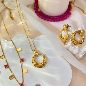 Modern gold irregular necklace and earring set with red gemstone beads on white prop