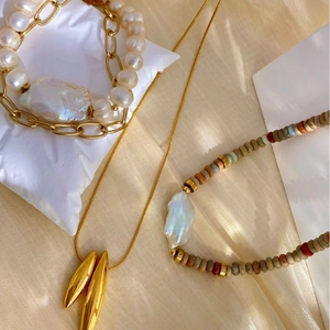 Bracciale di perle barocche e collana con ciondolo a goccia su sfondo di seta morbida