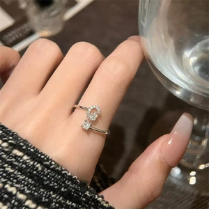 Dettaglio dell'anello regolabile in titanio argento con lettera G in zircone sulla mano