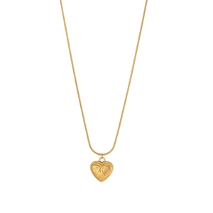 Dettaglio di un ciondolo a cuore dorato con decori vintage su una catena sottile