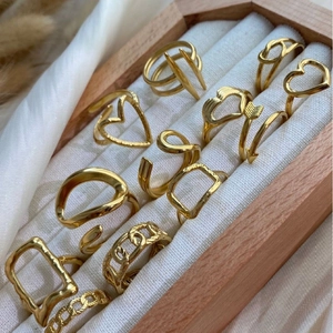 Set of gold minimalist stainless steel rings featuring heart and wave designs in a box