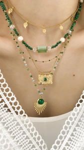 Detailed view of layered gold necklace set with green malachite beads and sun pendant