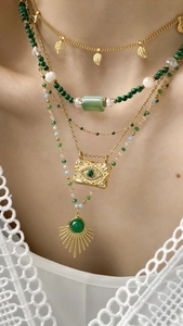 Close-up of layered vintage gold necklaces with malachite beads and sun pendant