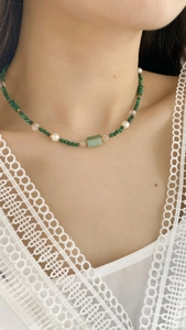 Detail of beaded necklace with green malachite, white pearls and a quartz stone pendant