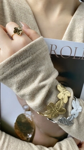 Gros plan d'un bracelet fleuri doré et argenté avec pétales texturés et bague assortie