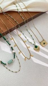 Detail of bohemian gold layered necklaces with green agate and sunburst pendants