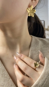 Détail d'un ensemble boucles d'oreilles et bague fleur en or brossé fini mat