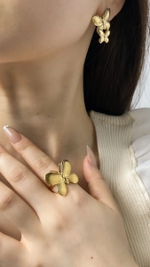 Gros plan de bagues et boucles d'oreilles papillon dorées sur un mannequin élégant