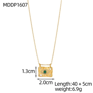 Detail view of a gold rectangular pendant with green stone and devil eye texture