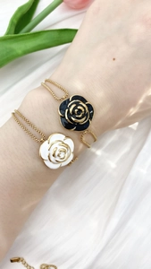 Detail der Kamelien-Armbänder in Schwarz und Weiß Emaille mit goldener Kette