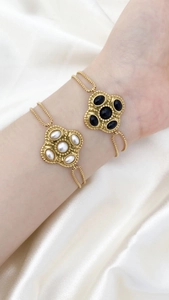 Nahaufnahme von Vintage-Blumenarmbändern mit weißem Perlen- und schwarzem Achatinlay