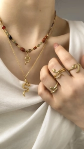 Nahaufnahme der goldenen Schlangen-Halskette mit Natursteinperlen an einem Frauenmodell