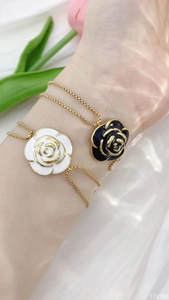 Nahaufnahme eleganter Kamelienblüten-Armbänder in Schwarz-Weiß-Emaille auf weißer Seide