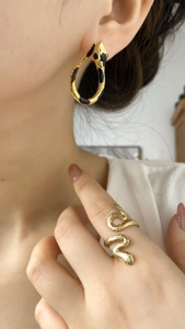 Details des Schlangen-Schmucksets mit goldenen Ohrringen und Ring am Modell