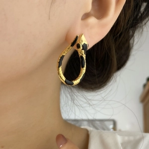 Goldene Schlangen-Ohrringe mit schwarzer Emaille getragen von weiblichem Model