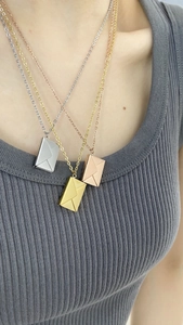 Detalle de los collares con colgante de sobre en acabados oro, plata y rosa