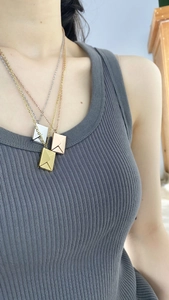 Tres collares con colgante de sobre en oro, oro rosa y plata lucidos por una modelo