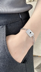Detalle de pulsera sobre plateada con circonitas y piedra negra en cadena de eslabones curb