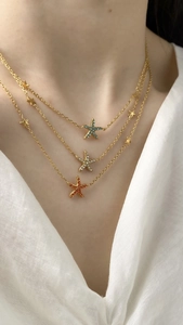 Detailed close-up of a triple-layered gold necklace featuring three colorful starfish pendants