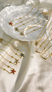 Detail of gold starfish necklaces with colorful rhinestones on a white satin background