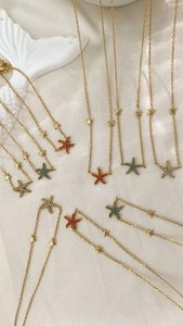Detailed view of layered starfish pendant necklaces with colorful zircons on white silk