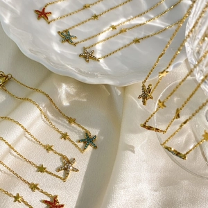 Elegant gold starfish necklace with colorful rhinestones on a white ceramic tray