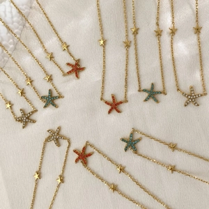 Starfish gold necklaces with colorful crystals on a soft white silk background